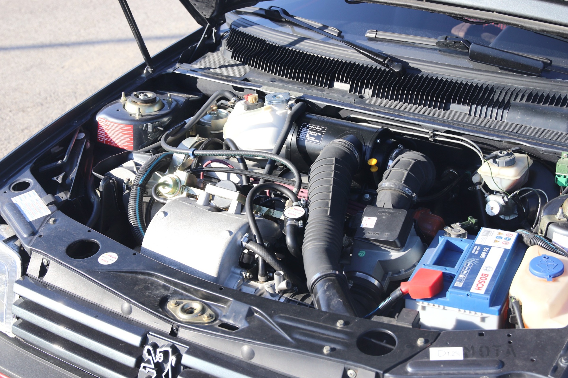 Compartiment moteur d'une Peugeot 205 GTI 1.9 propre avec batterie Bosch et boîtier filtre à air