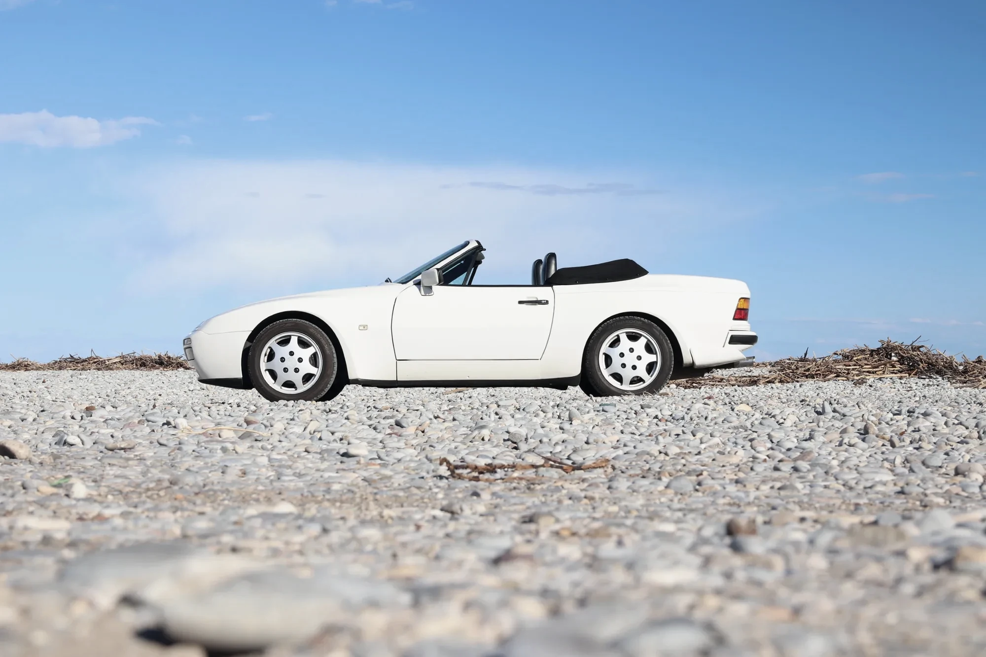 Porsche 944 cabriolet vue de profil sur galets, ligne basse années 80